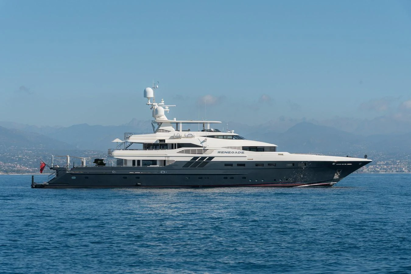 A sleek and modern yacht glides gracefully on calm waters with a scenic backdrop. aboard RENEGADE Yacht for Sale