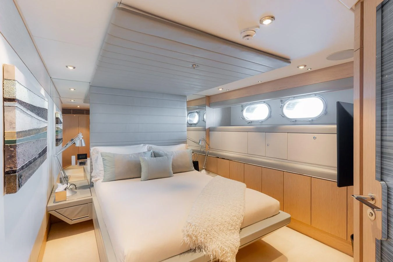 The stateroom features a plush bed, modern decor, and ample natural light from the portholes. aboard RENEGADE Yacht for Sale