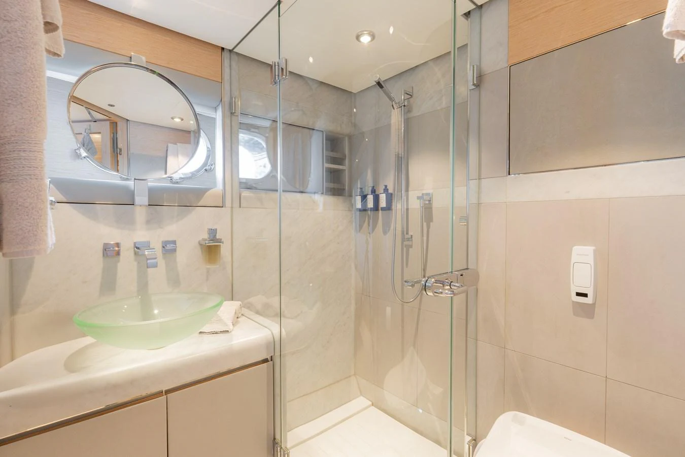 The yacht's bathroom features a modern glass-enclosed shower and a sleek vanity with a glass basin. aboard RENEGADE Yacht for Sale