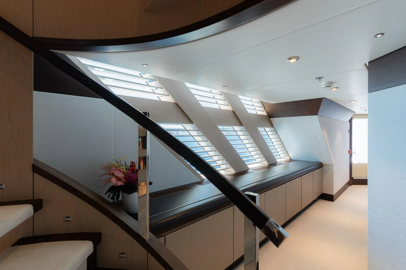 A modern yacht interior featuring a sleek staircase and large windows allowing ample natural light. aboard RENEGADE Yacht for Sale