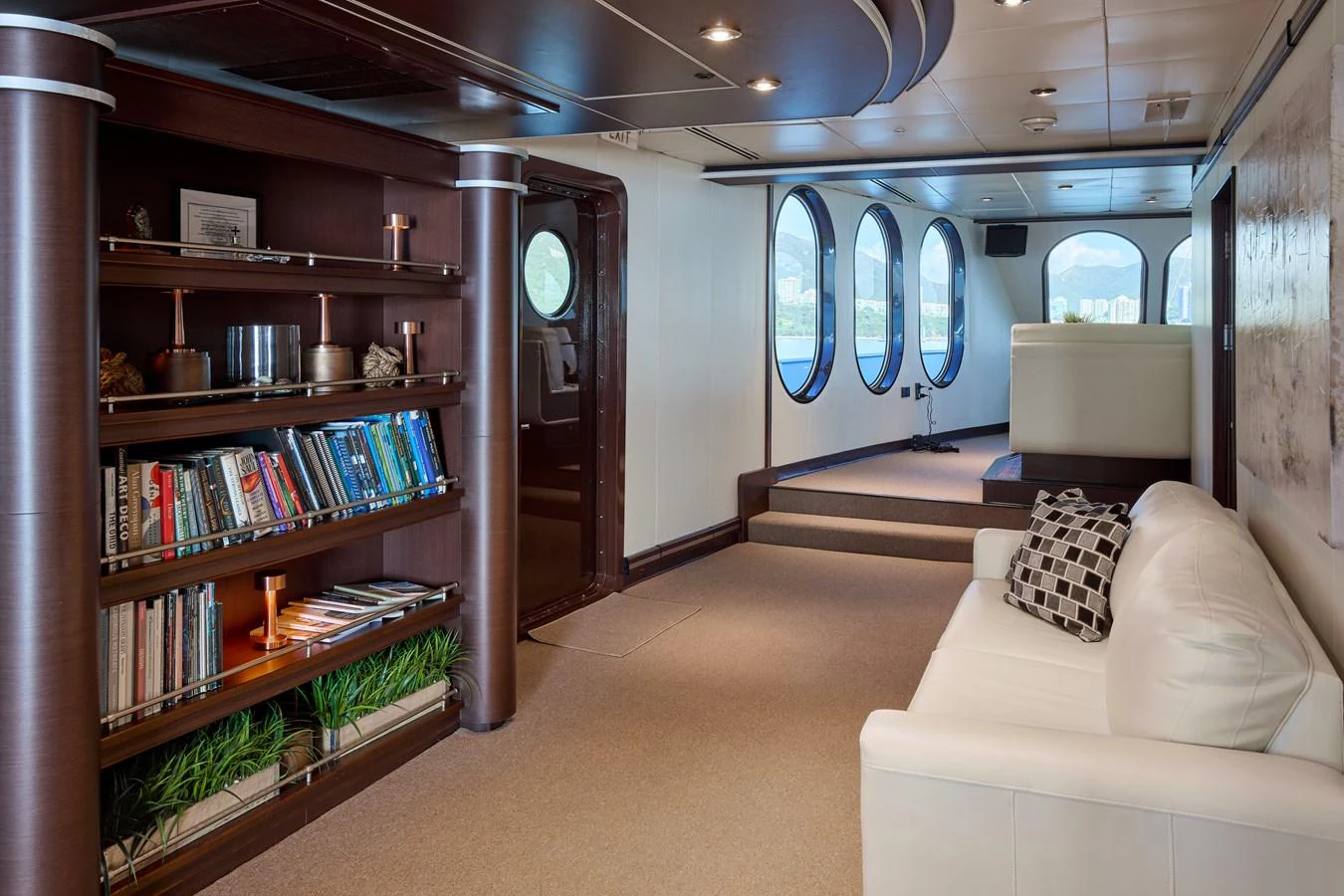The yacht's interior features a cozy lounge area with a bookshelf and comfortable seating. aboard GLOBAL Yacht for Sale