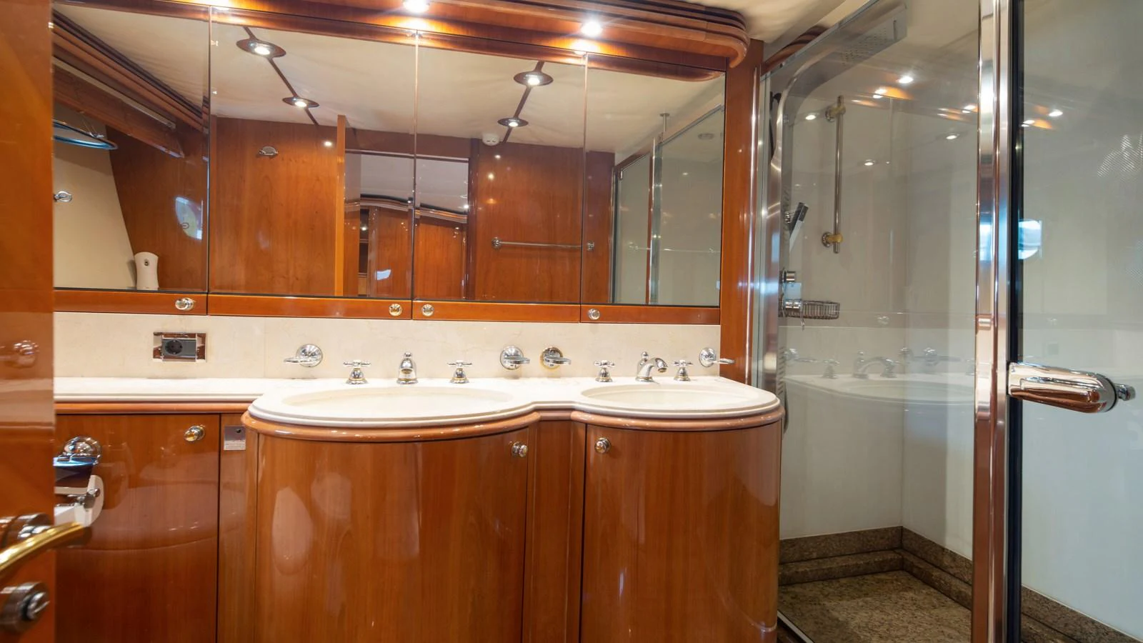 The yacht's bathroom features elegant wooden cabinetry, dual sinks, and a spacious glass-enclosed shower. aboard MI ALMA Yacht for Sale
