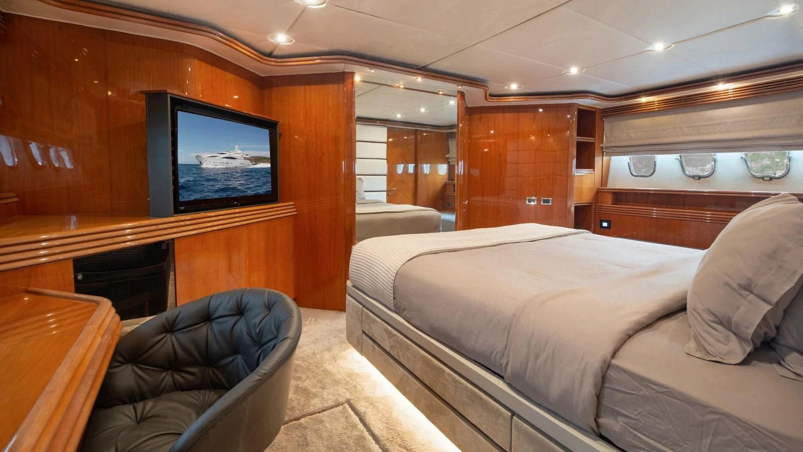 The master stateroom features luxurious wood paneling, a plush bed, and a flat-screen TV. aboard MI ALMA Yacht for Sale
