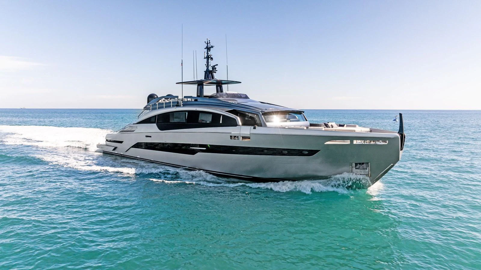 A sleek and modern yacht cruises swiftly on clear blue waters under a bright sky. aboard CAFFEINE Yacht for Sale