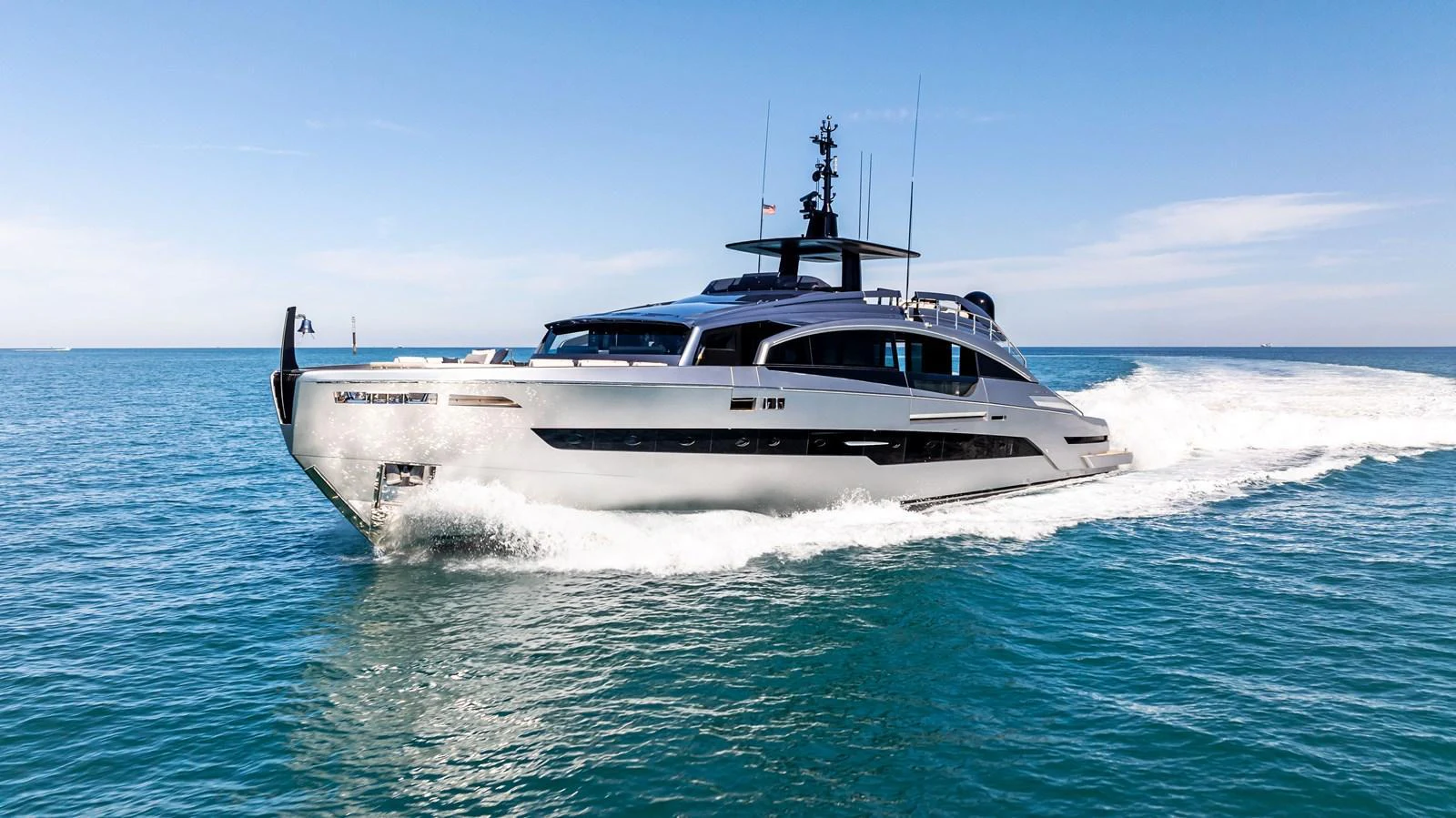 A sleek and modern yacht cruises swiftly on calm blue waters under a clear sky. aboard CAFFEINE Yacht for Sale