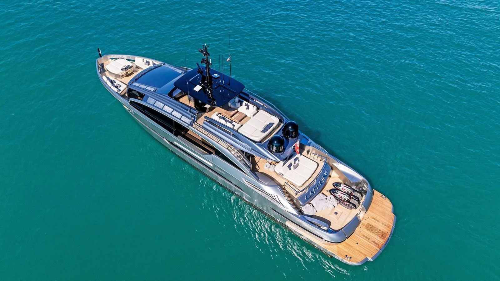 A sleek yacht glides through clear blue waters, showcasing its modern design and spacious deck. aboard CAFFEINE Yacht for Sale