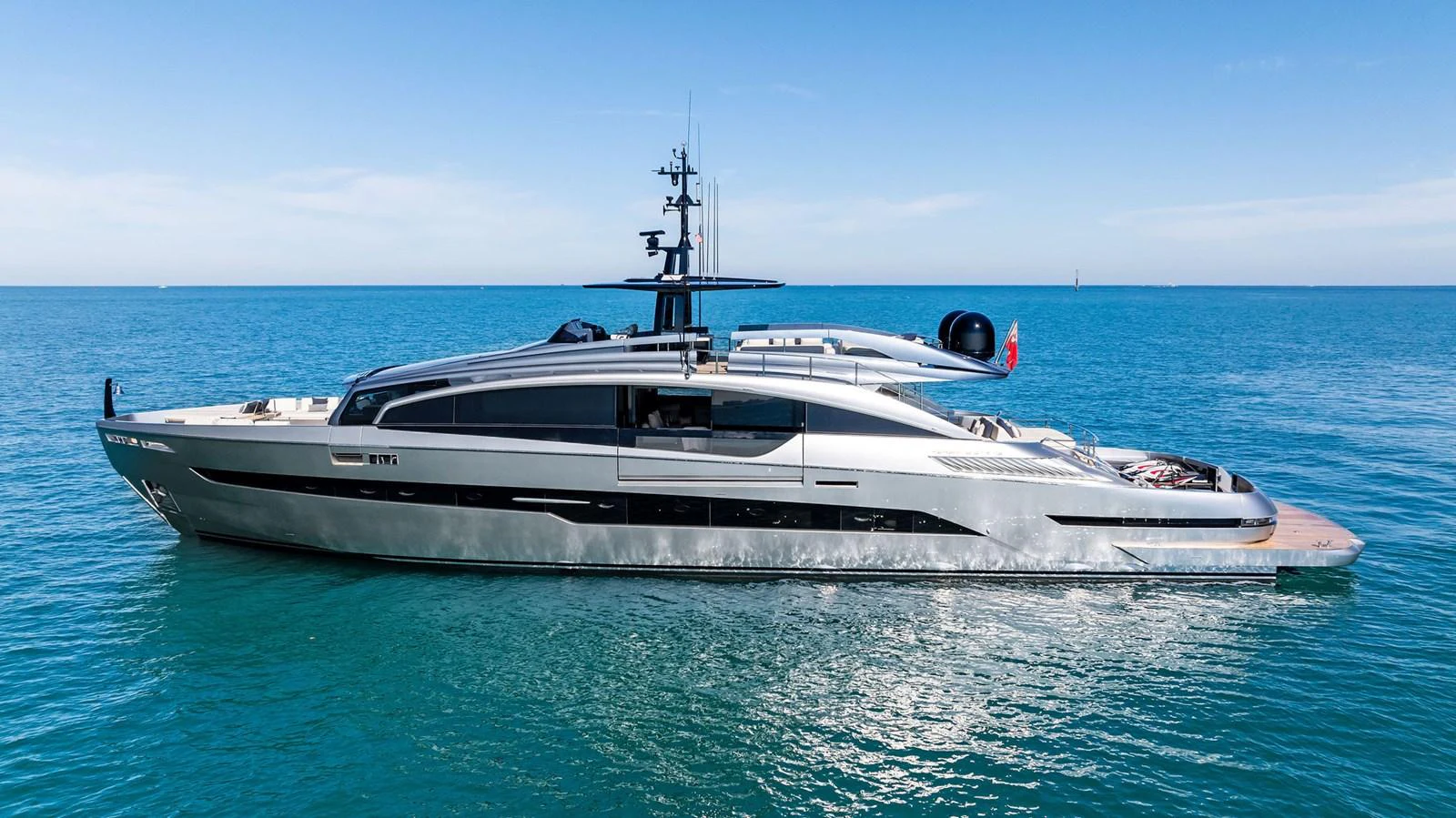 A sleek and modern yacht glides gracefully on calm blue waters under a clear sky. aboard CAFFEINE Yacht for Sale