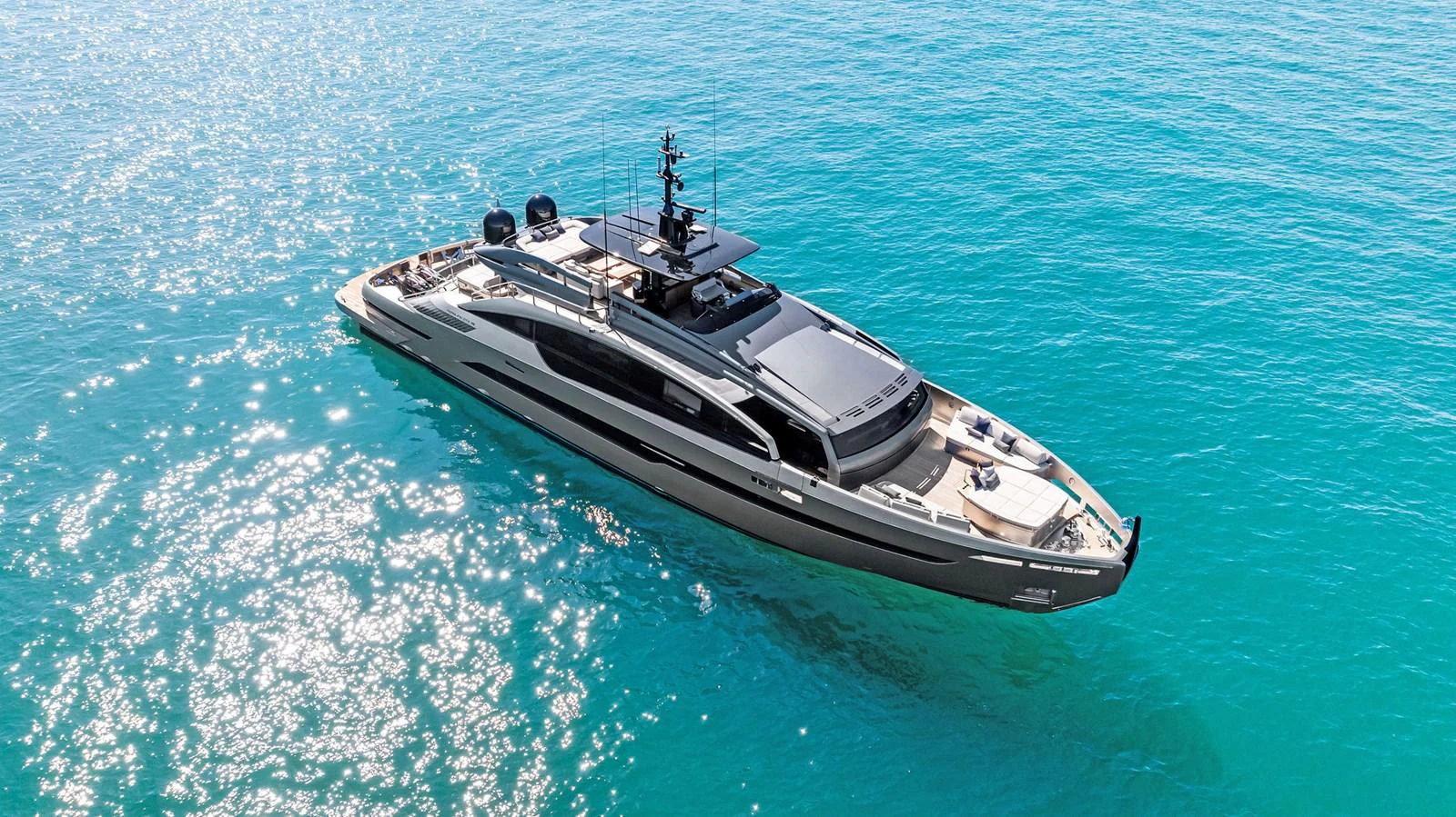 A sleek, modern yacht glides gracefully on clear turquoise waters under the bright sun. aboard CAFFEINE Yacht for Sale