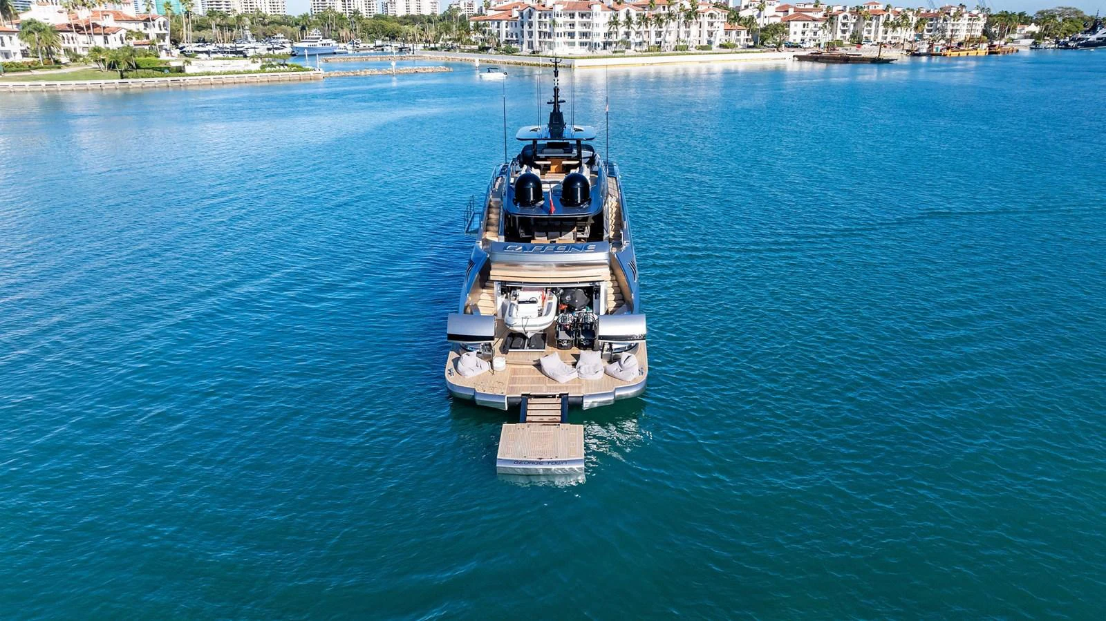 A luxurious yacht is anchored in a serene marina with a beautiful waterfront backdrop. aboard CAFFEINE Yacht for Sale