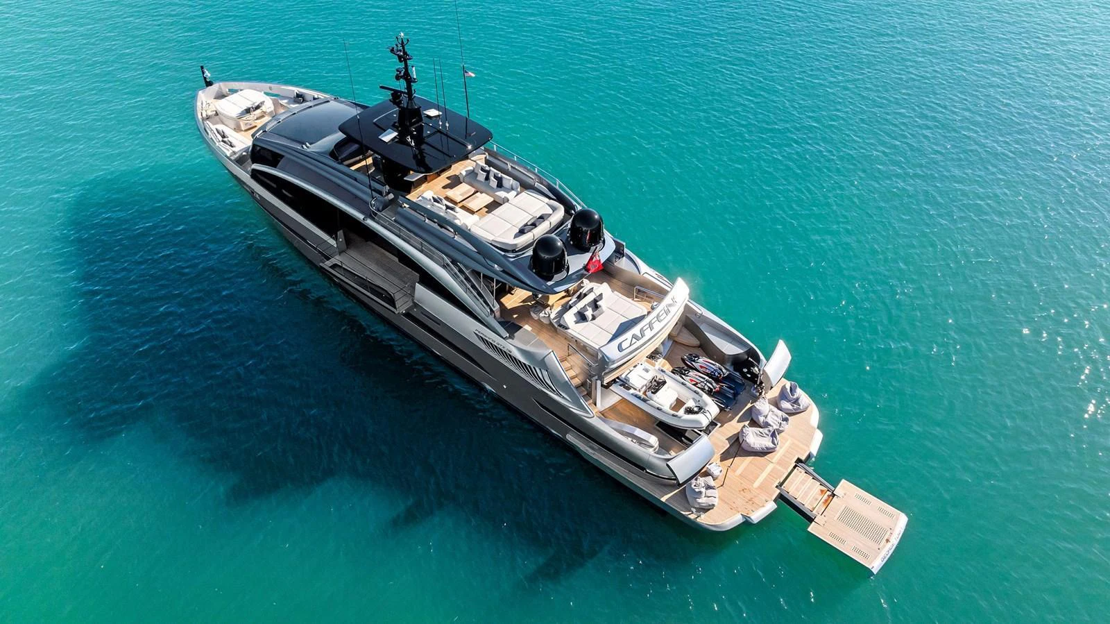 A sleek and modern yacht cruising on clear blue waters, showcasing its luxurious design and spacious deck areas. aboard CAFFEINE Yacht for Sale