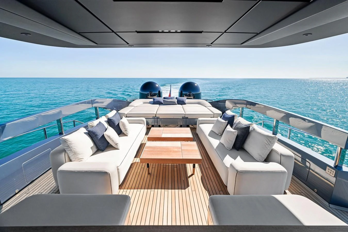 The aft deck offers a luxurious seating area with plush sofas and a wooden table, perfect for relaxation and socializing while enjoying the ocean view. aboard CAFFEINE Yacht for Sale