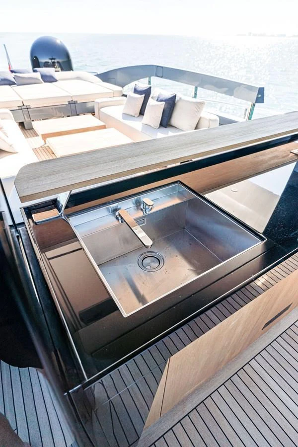 The yacht features a sleek outdoor galley with a stainless steel sink and comfortable seating area. aboard CAFFEINE Yacht for Sale