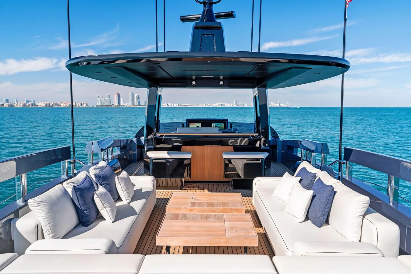 The yacht's aft deck features luxurious seating with a stunning view of the ocean and city skyline. aboard CAFFEINE Yacht for Sale