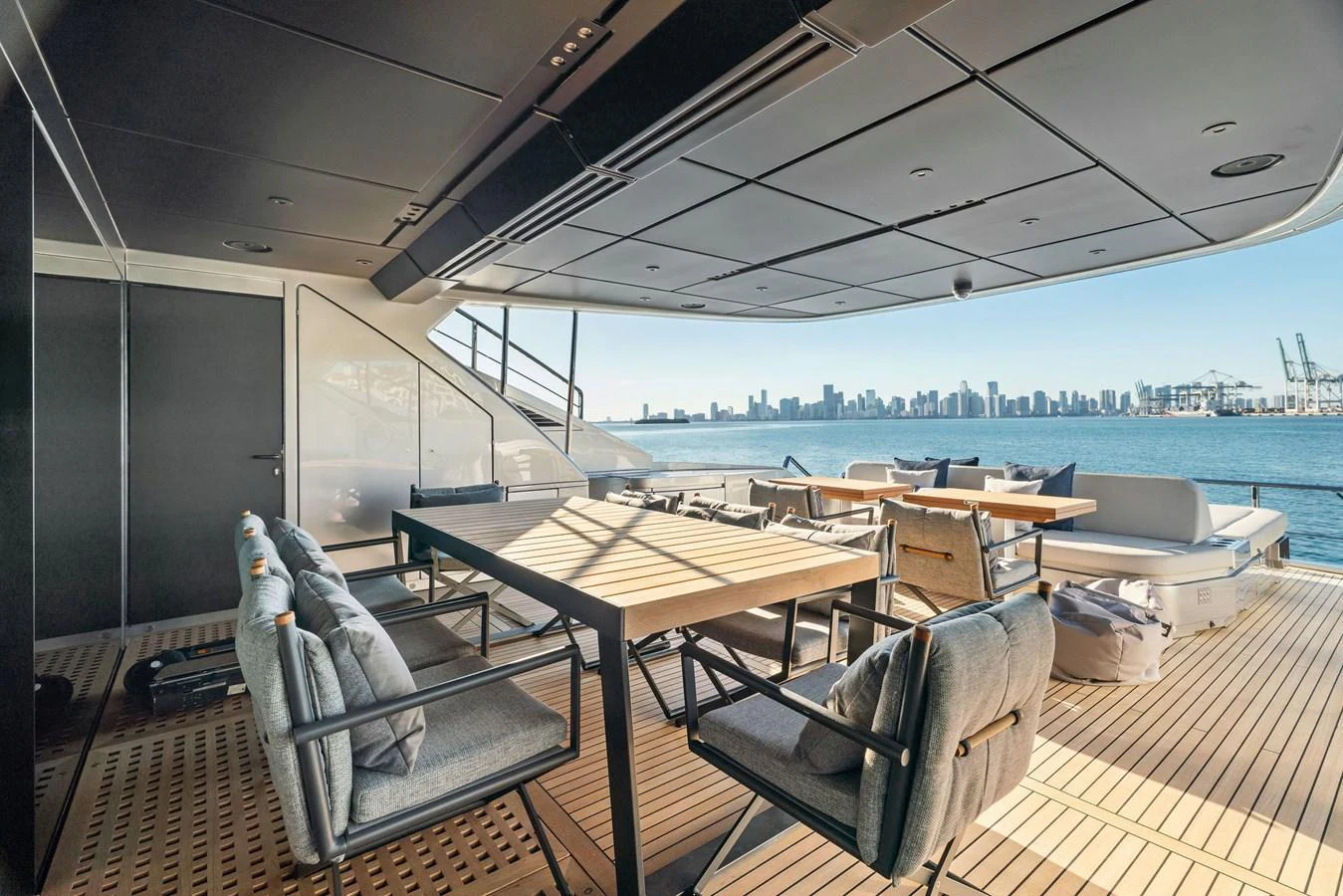 The aft deck features a spacious dining area with comfortable seating and stunning views of the city skyline. aboard CAFFEINE Yacht for Sale