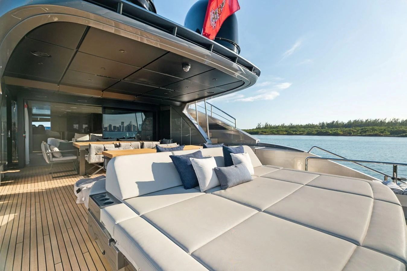 The aft deck features a spacious sunbathing area with plush cushions and a dining table for alfresco meals. aboard CAFFEINE Yacht for Sale