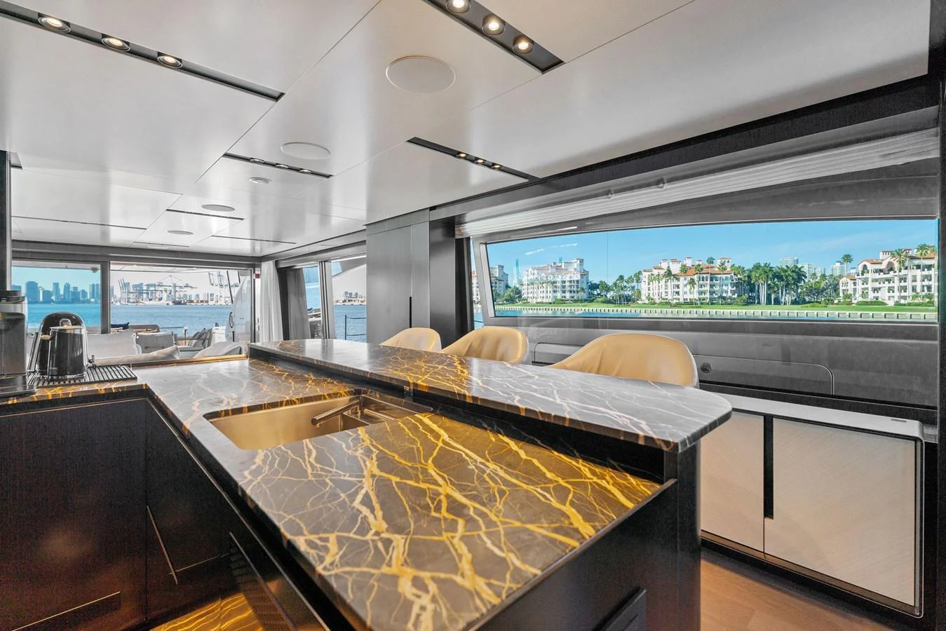The yacht's galley features a luxurious marble countertop with a stunning view through large windows. aboard CAFFEINE Yacht for Sale