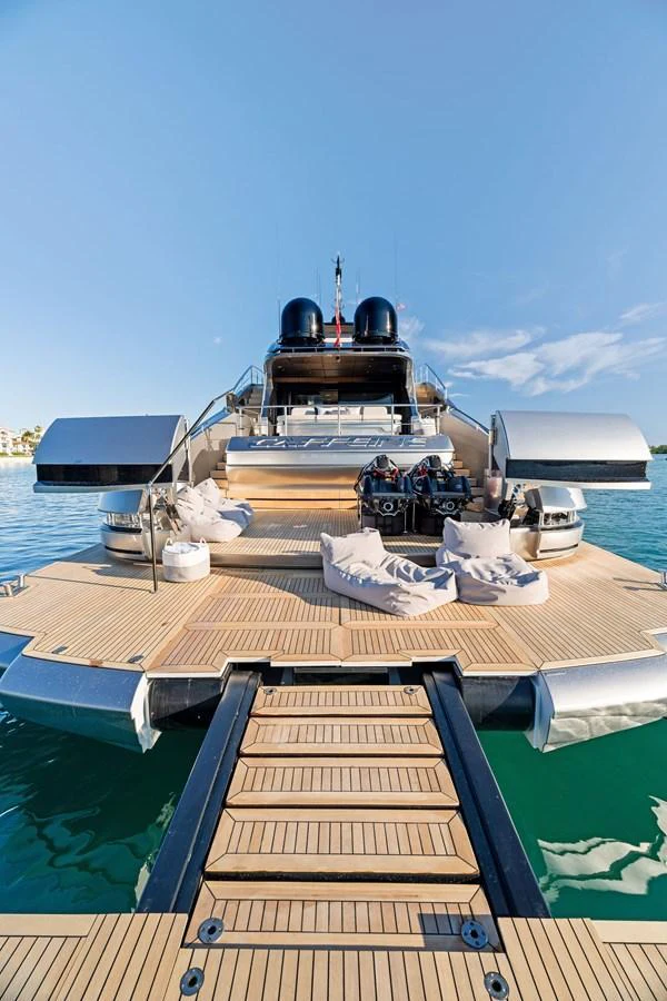 The yacht's aft deck features a luxurious lounging area with plush seating and direct access to the water. aboard CAFFEINE Yacht for Sale