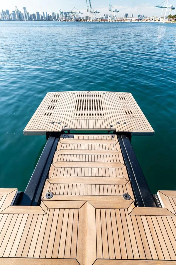 The yacht features a sleek swim platform with a view of the city skyline in the background. aboard CAFFEINE Yacht for Sale