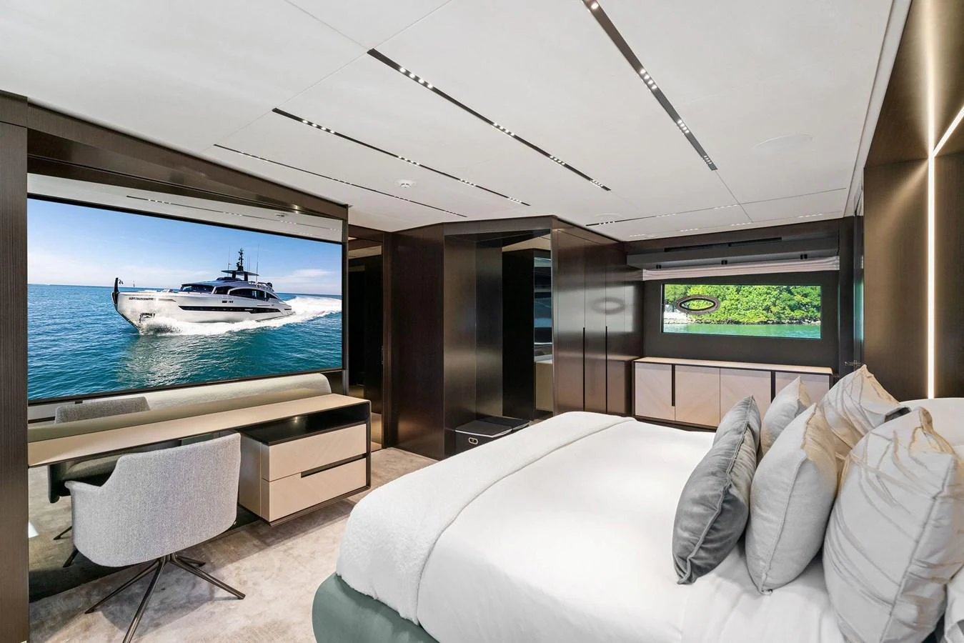The luxurious stateroom features a large bed, modern furnishings, and a flat-screen TV displaying a yacht on the water. aboard CAFFEINE Yacht for Sale