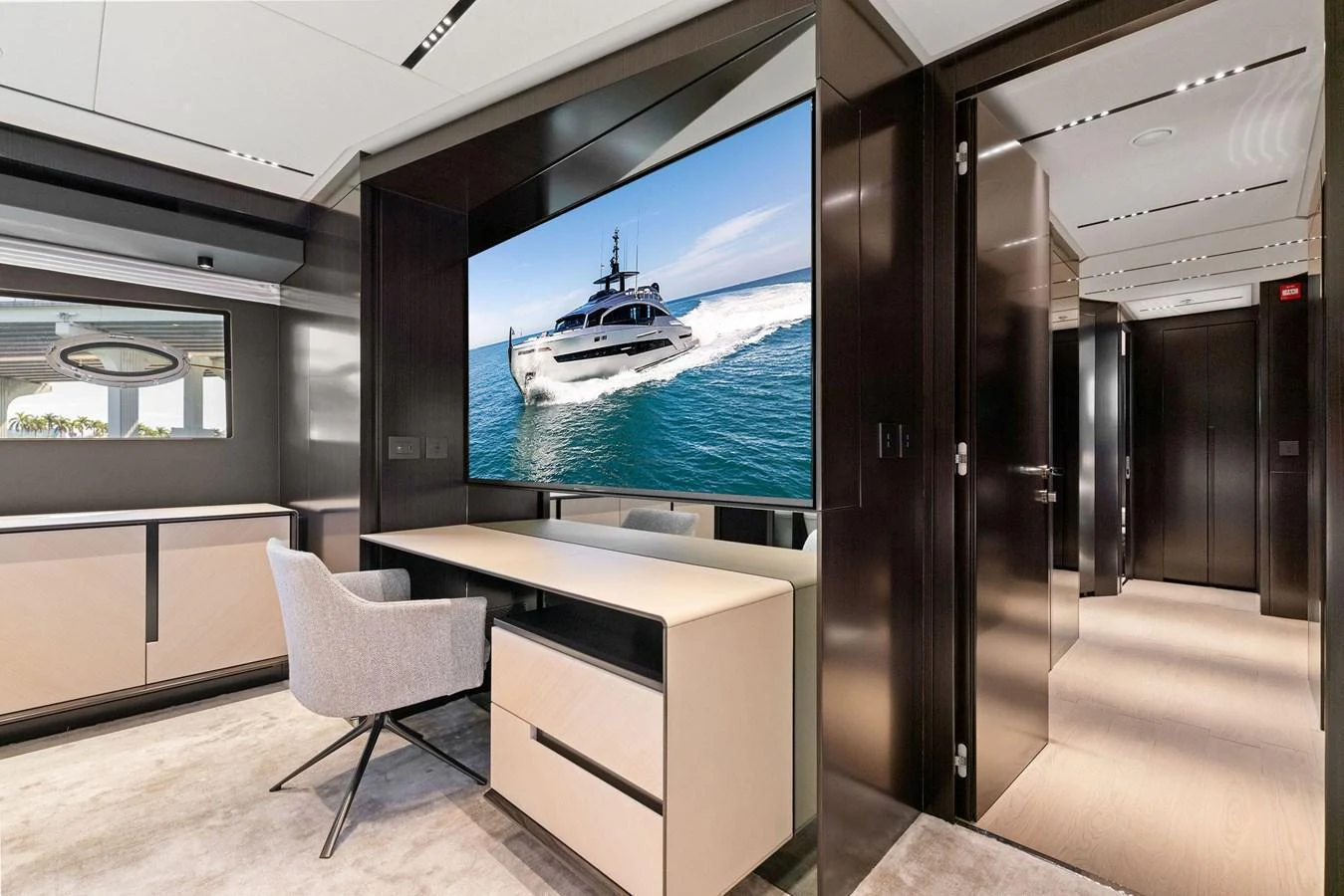 A luxurious interior space featuring a large flat-screen TV displaying a yacht, with modern furnishings and sleek design elements. aboard CAFFEINE Yacht for Sale
