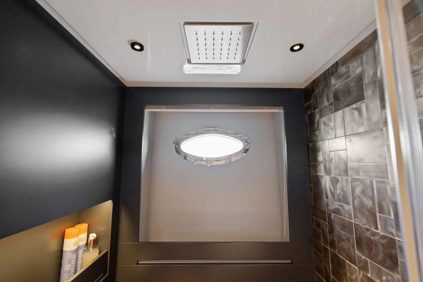 A sleek and modern yacht bathroom with a porthole window and contemporary fixtures. aboard CAFFEINE Yacht for Sale