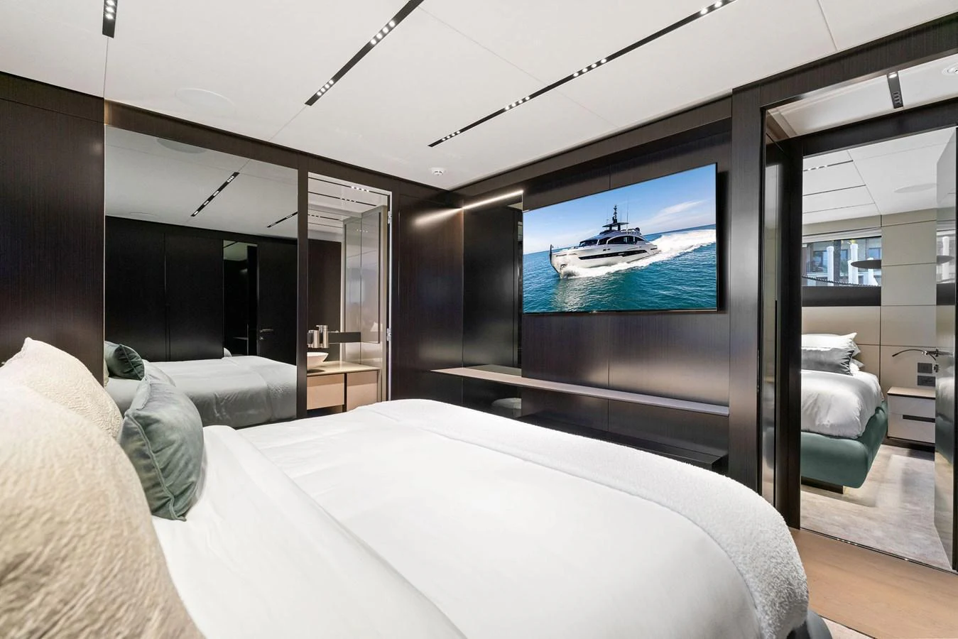 A luxurious stateroom featuring a large bed, modern decor, and a flat-screen TV displaying a yacht. aboard CAFFEINE Yacht for Sale