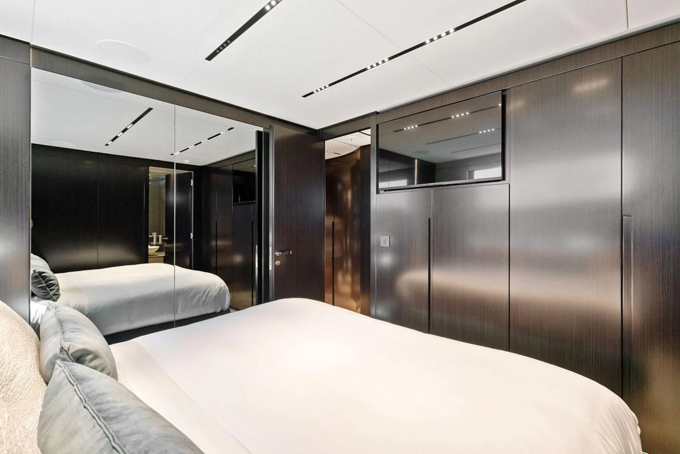 A luxurious stateroom featuring sleek, dark wood paneling and a plush bed. aboard CAFFEINE Yacht for Sale