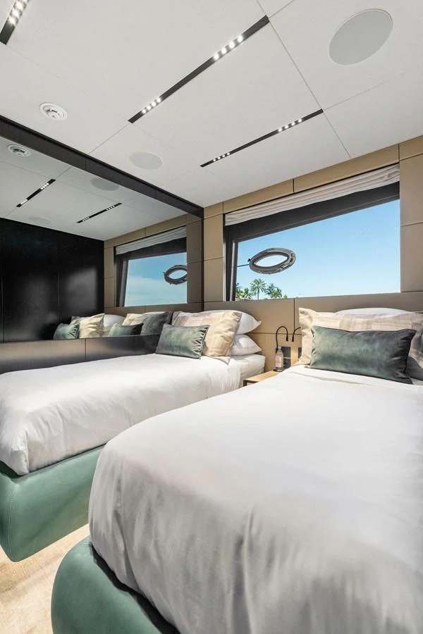 The guest stateroom features twin beds with luxurious bedding and large windows offering a scenic view. aboard CAFFEINE Yacht for Sale