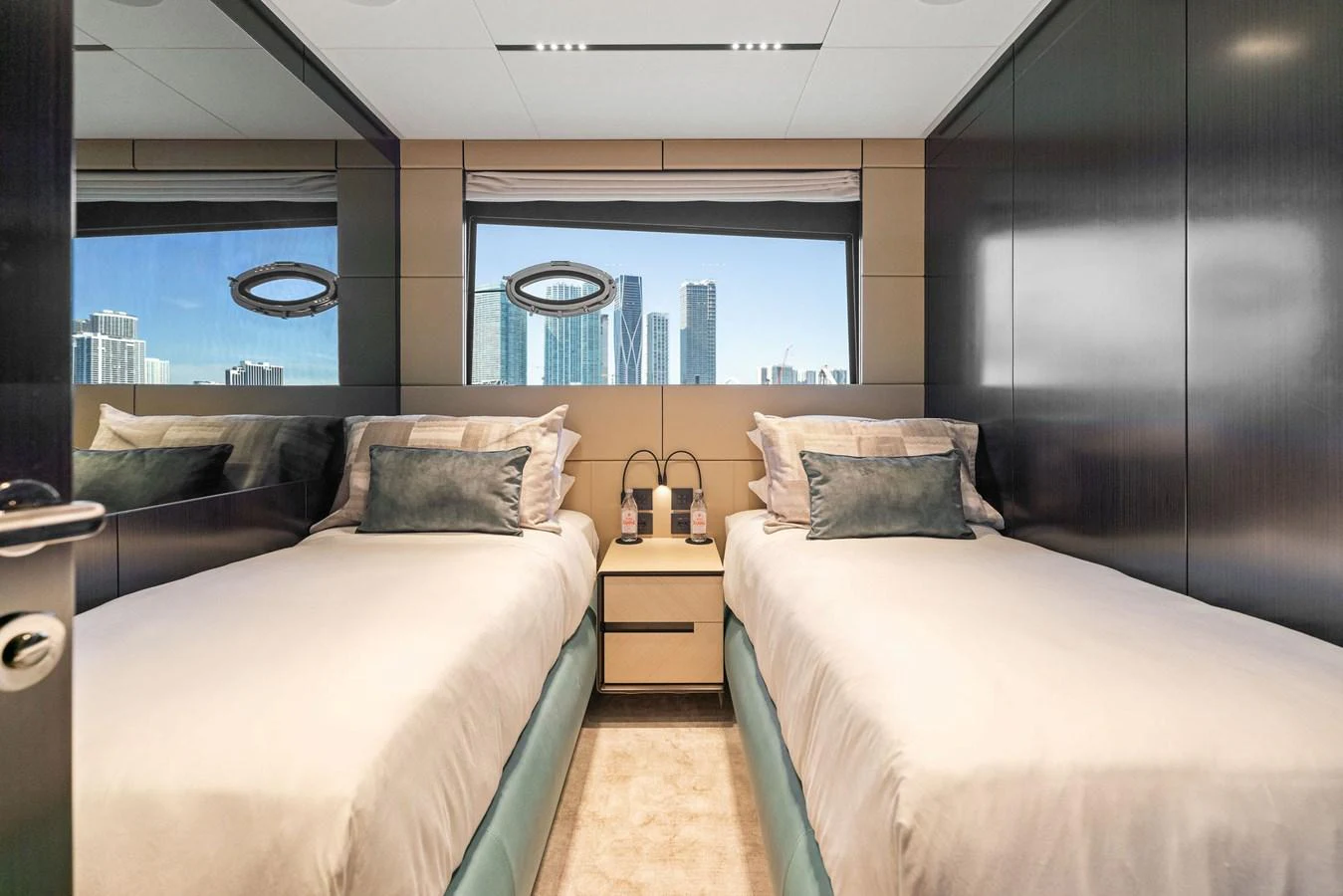 The twin stateroom offers a serene retreat with a stunning cityscape view through the large window. aboard CAFFEINE Yacht for Sale