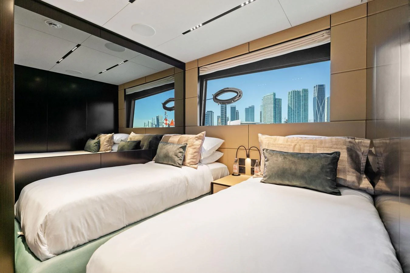 The guest stateroom features twin beds with a large window offering a cityscape view. aboard CAFFEINE Yacht for Sale