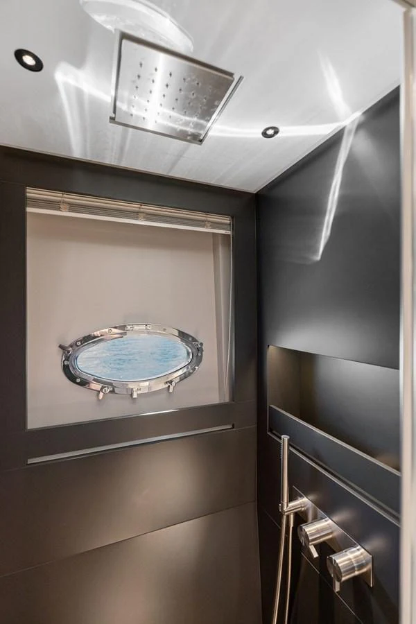 A sleek and modern yacht bathroom with a porthole window and contemporary fixtures. aboard CAFFEINE Yacht for Sale
