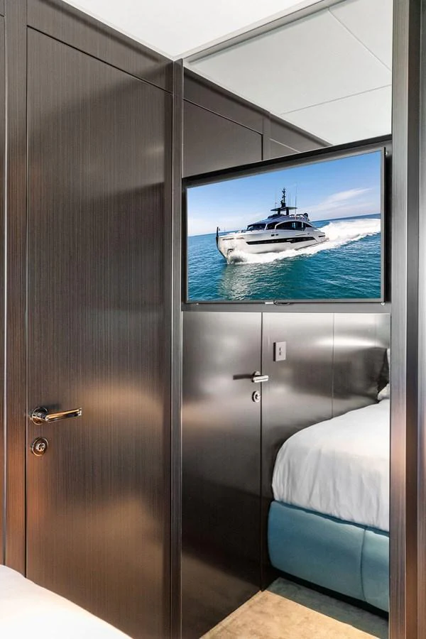 A cozy stateroom with a mounted television displaying a yacht on the water. aboard CAFFEINE Yacht for Sale