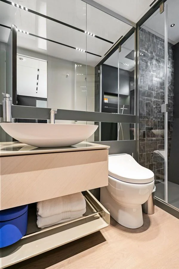 A modern yacht bathroom featuring a sleek sink, toilet, and glass-enclosed shower. aboard CAFFEINE Yacht for Sale