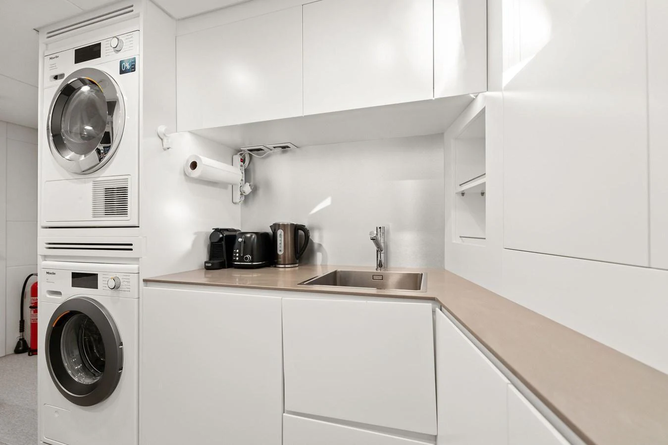 A modern yacht galley featuring sleek white cabinetry and essential appliances. aboard CAFFEINE Yacht for Sale