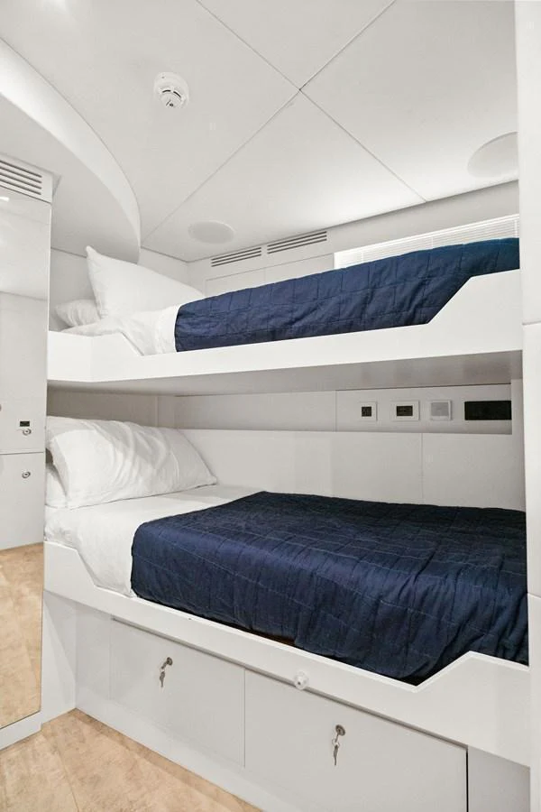 The guest cabin features cozy bunk beds with crisp white and navy linens. aboard CAFFEINE Yacht for Sale