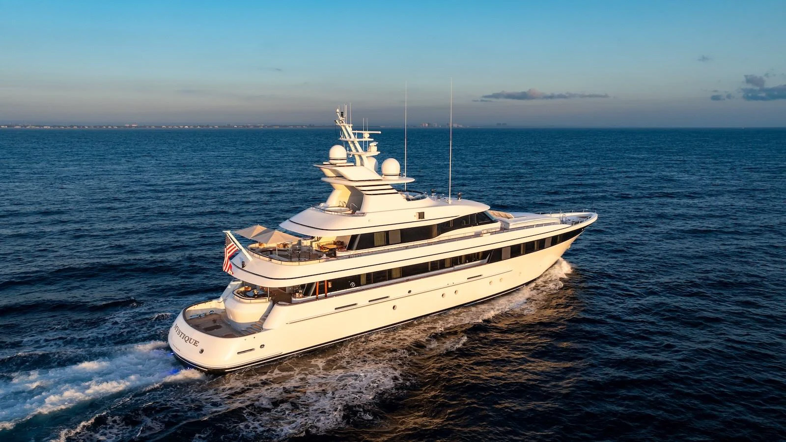 A luxurious yacht cruises through the open sea at sunset, showcasing its elegant design and spacious decks. aboard MYSTIQUE Yacht for Sale