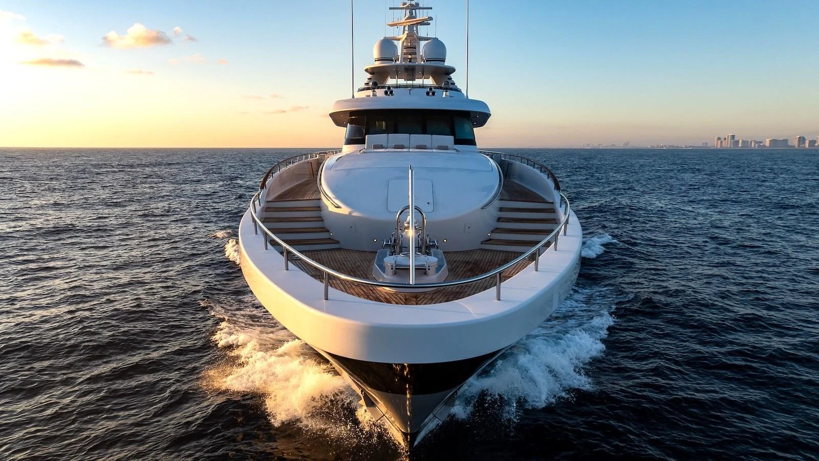 A majestic yacht cruises forward on the open sea at sunset. aboard MYSTIQUE Yacht for Sale