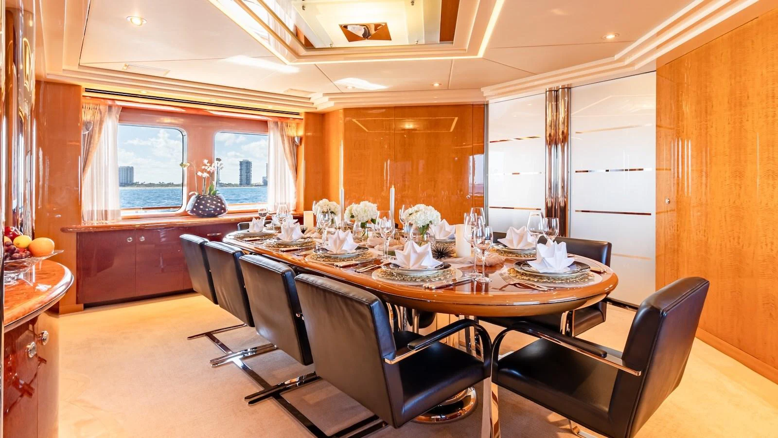 The yacht's dining area features a beautifully set table with elegant decor and large windows offering a scenic view. aboard MYSTIQUE Yacht for Sale