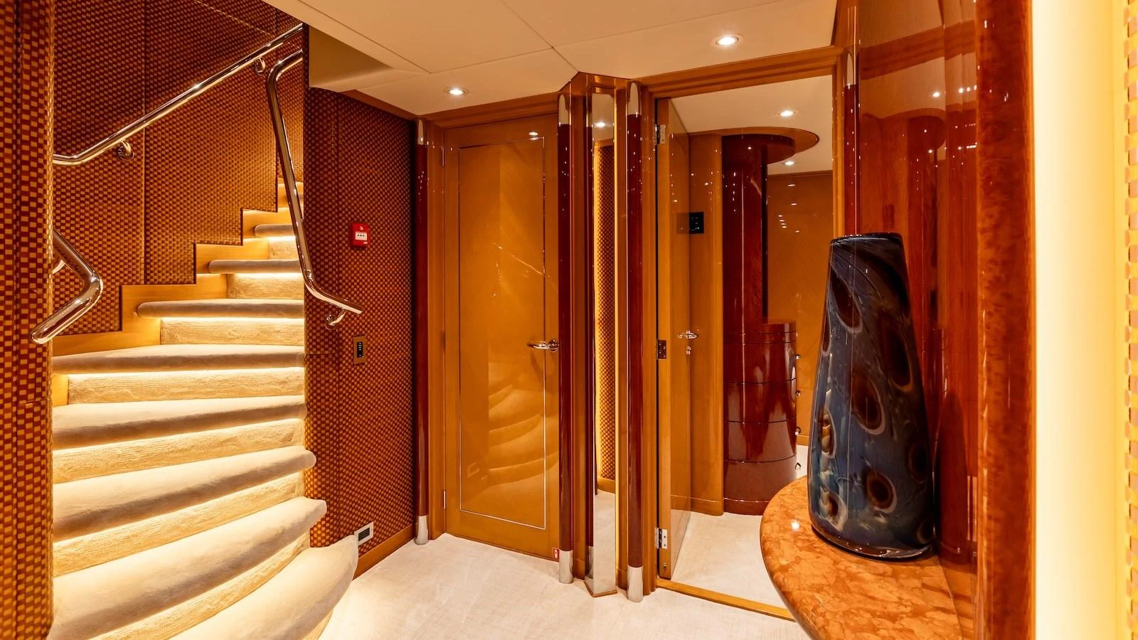 The yacht's interior features a luxurious staircase and polished wooden finishes. aboard MYSTIQUE Yacht for Sale