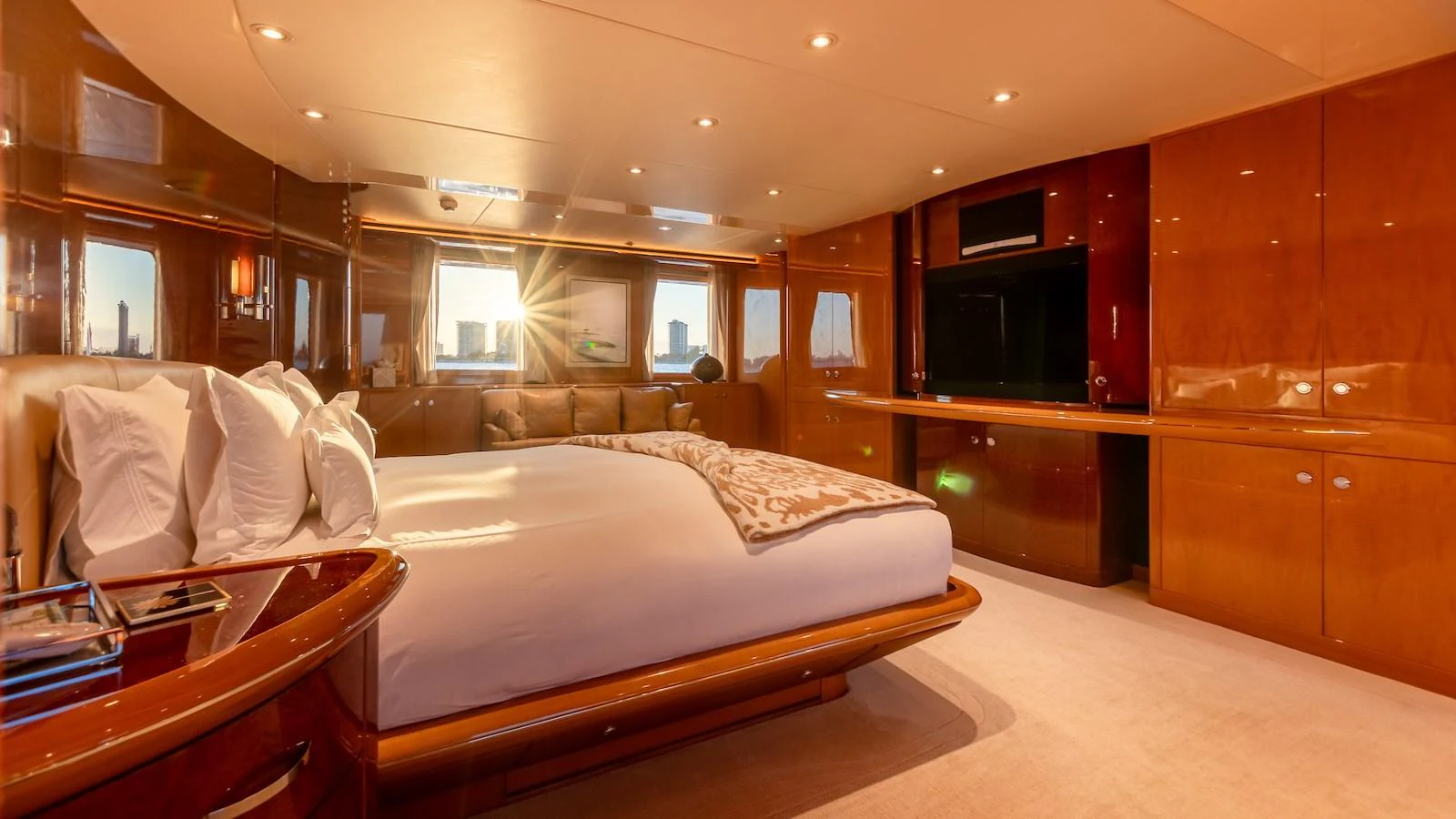 The master stateroom features a luxurious bed, warm wood finishes, and ample natural light. aboard MYSTIQUE Yacht for Sale