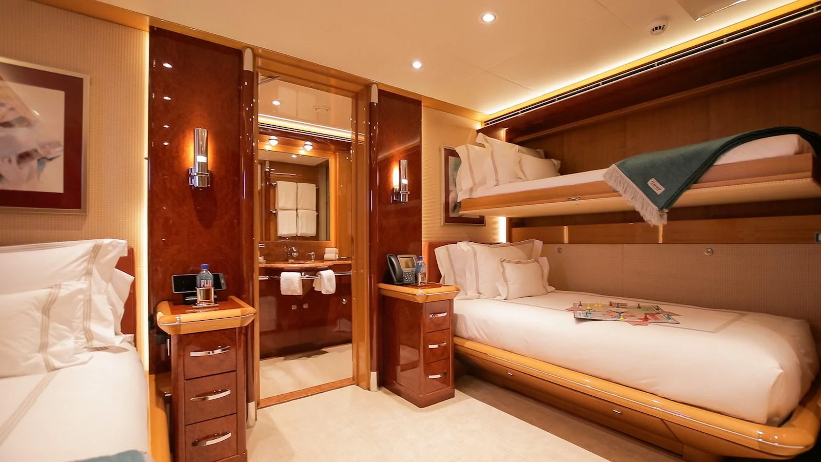 The guest stateroom features cozy twin beds and elegant wood finishes, offering a comfortable and inviting space. aboard MYSTIQUE Yacht for Sale