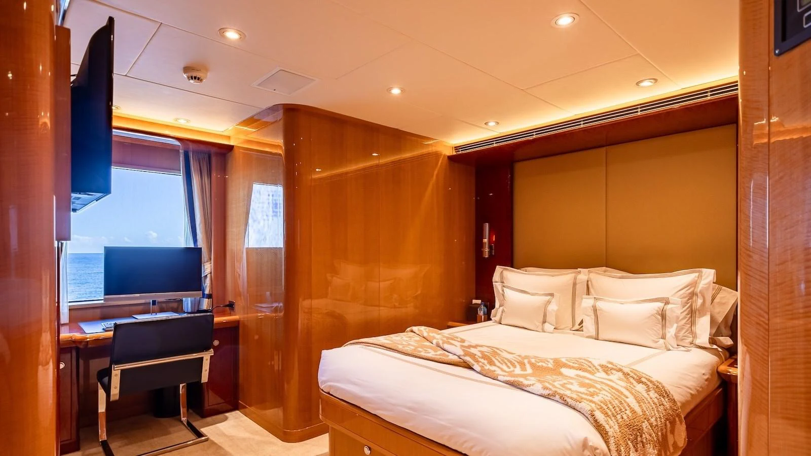 The stateroom features a luxurious bed with plush linens and a well-appointed workspace by the window. aboard MYSTIQUE Yacht for Sale