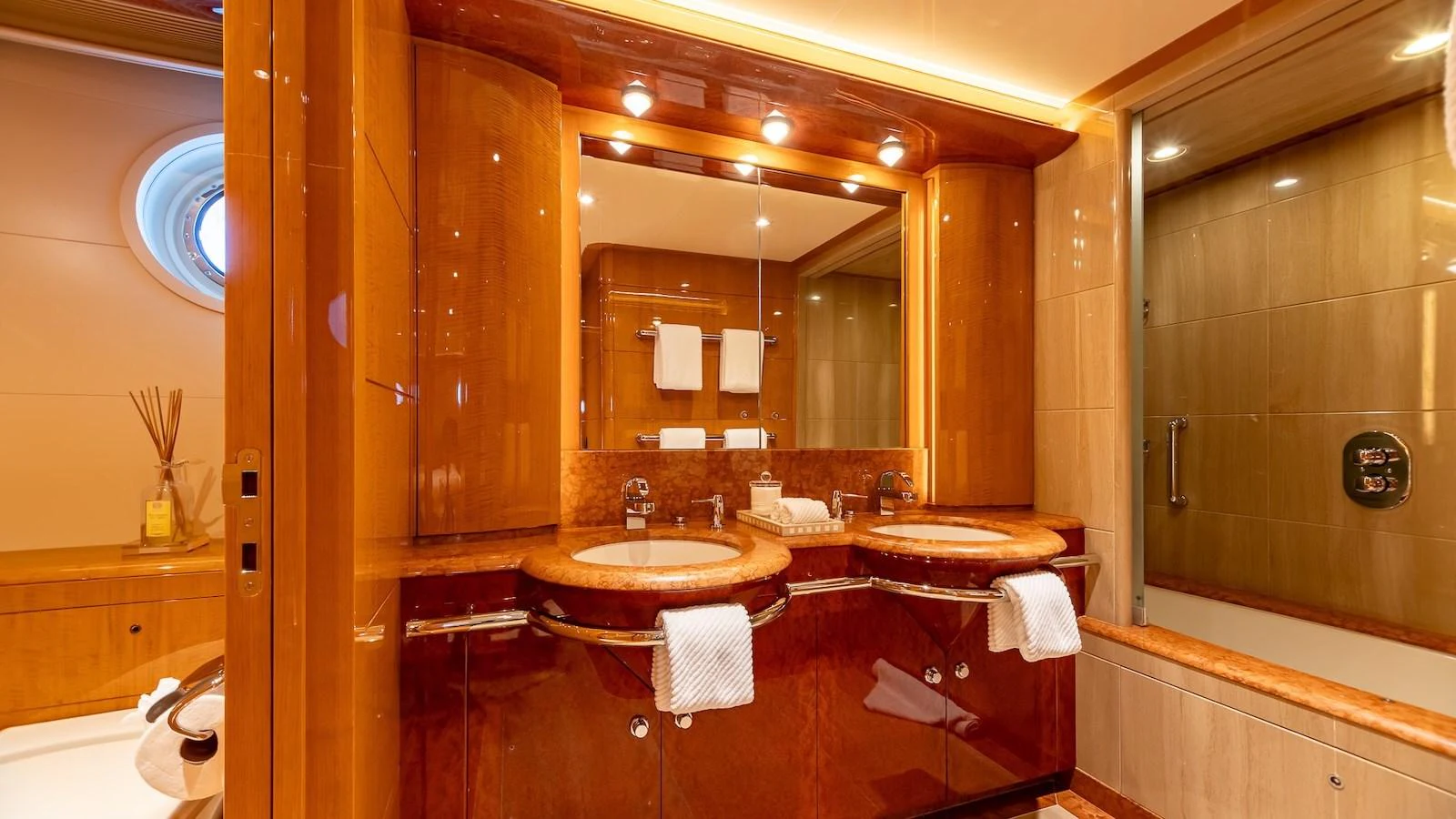 The yacht's bathroom features elegant wood finishes and dual sinks, creating a luxurious and inviting space. aboard MYSTIQUE Yacht for Sale