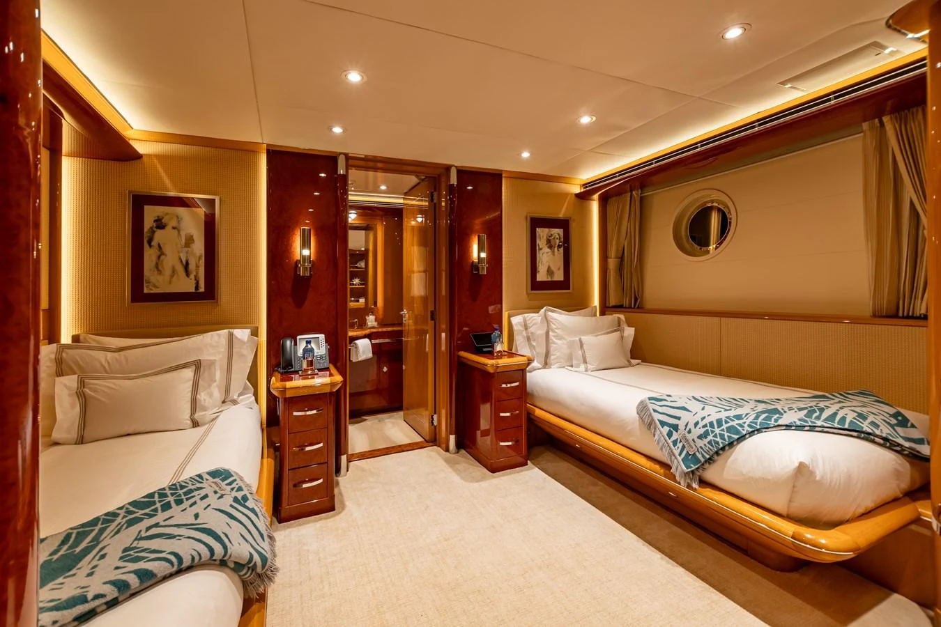 The guest stateroom features twin beds, warm lighting, and elegant wood finishes. aboard MYSTIQUE Yacht for Sale