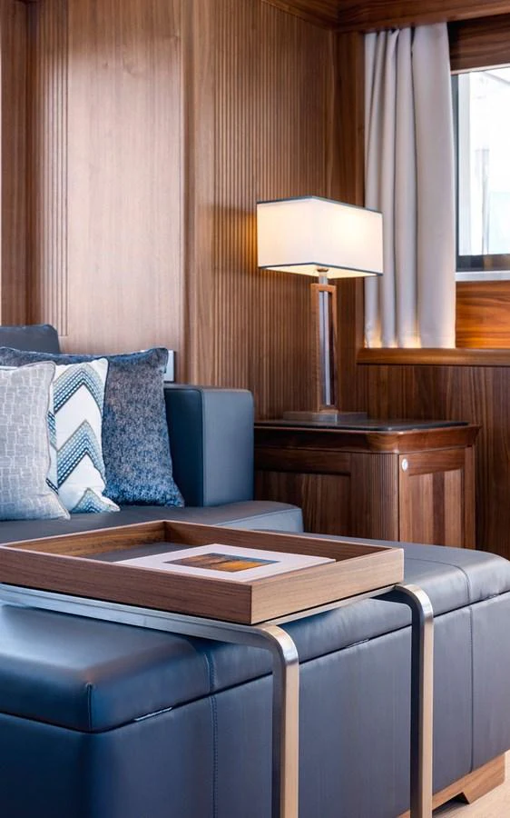 The yacht's interior features a cozy seating area with elegant wood paneling and a modern lamp. aboard EMPIRE Yacht for Sale