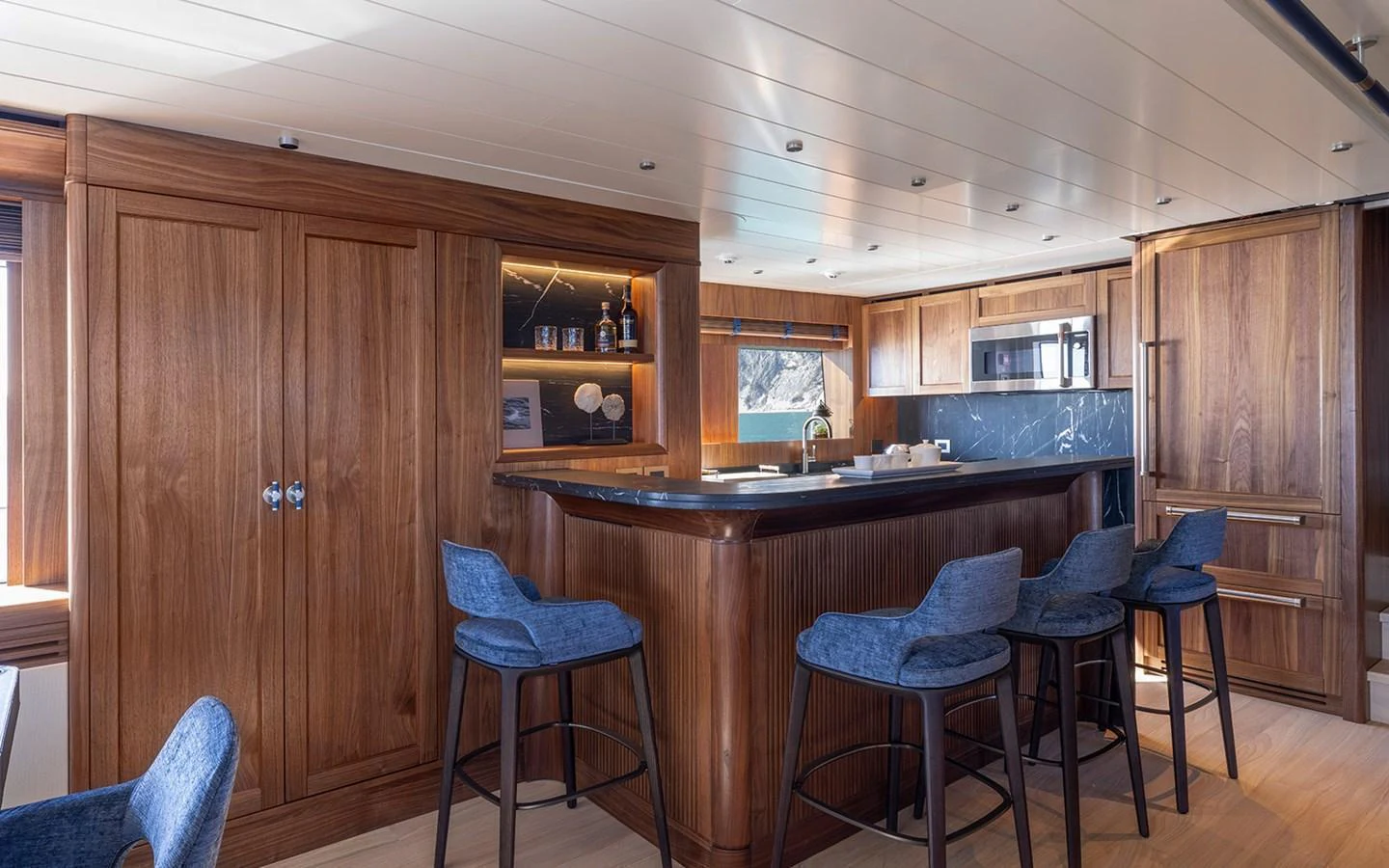 The yacht's galley features a stylish bar area with wooden cabinetry and blue bar stools. aboard EMPIRE Yacht for Sale