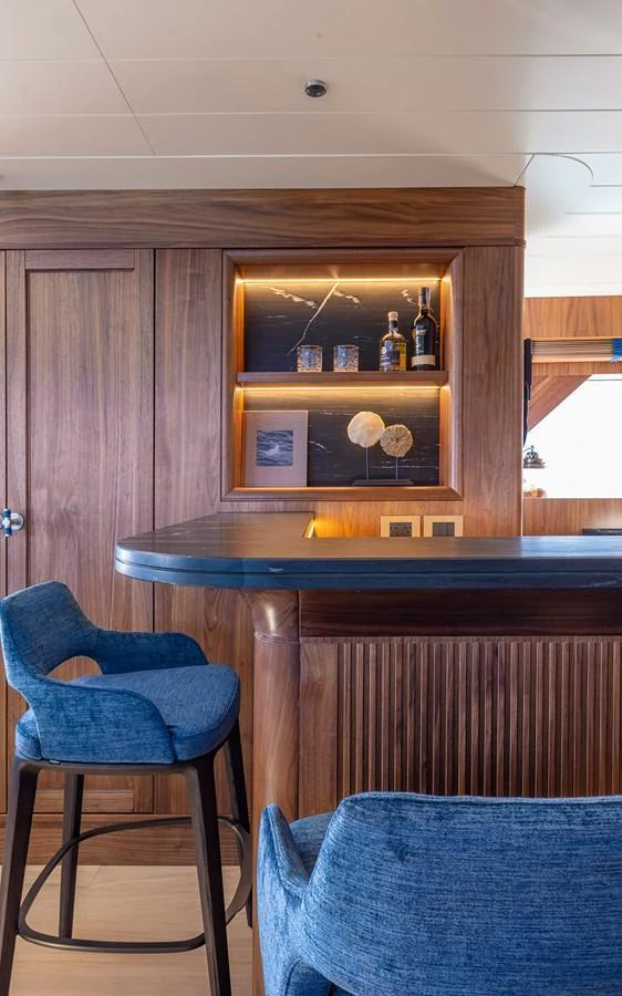 The yacht's interior features a stylish bar area with wooden finishes and blue seating. aboard EMPIRE Yacht for Sale