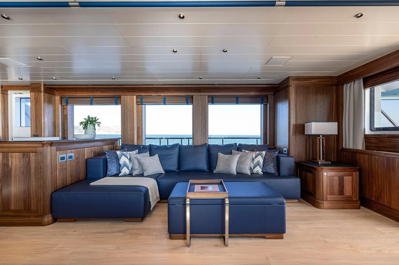 The yacht's salon features a spacious seating area with plush blue sofas and elegant wooden accents. aboard EMPIRE Yacht for Sale