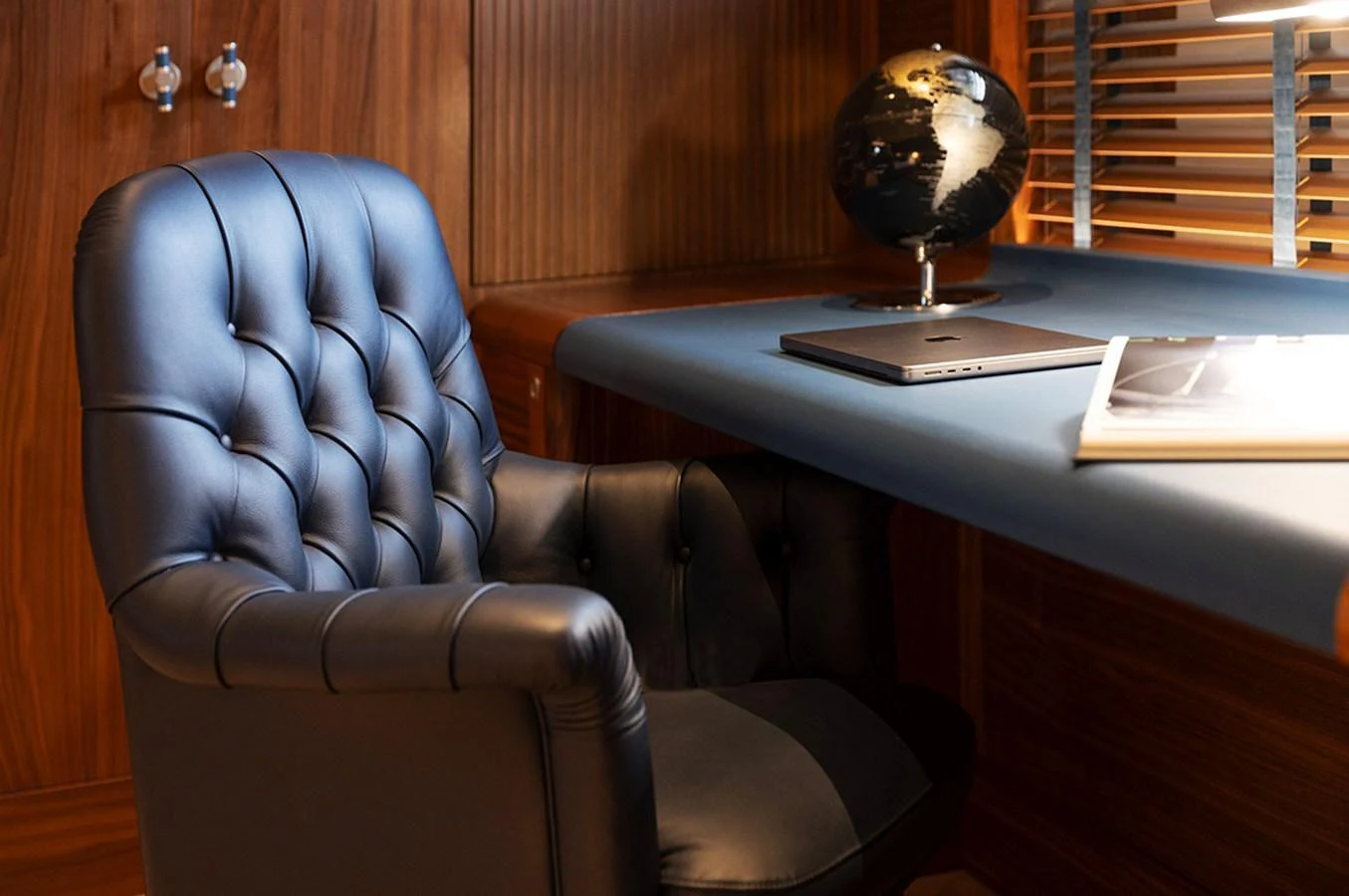 A luxurious study area featuring a plush leather chair and a sleek desk with a globe and a laptop. aboard EMPIRE Yacht for Sale
