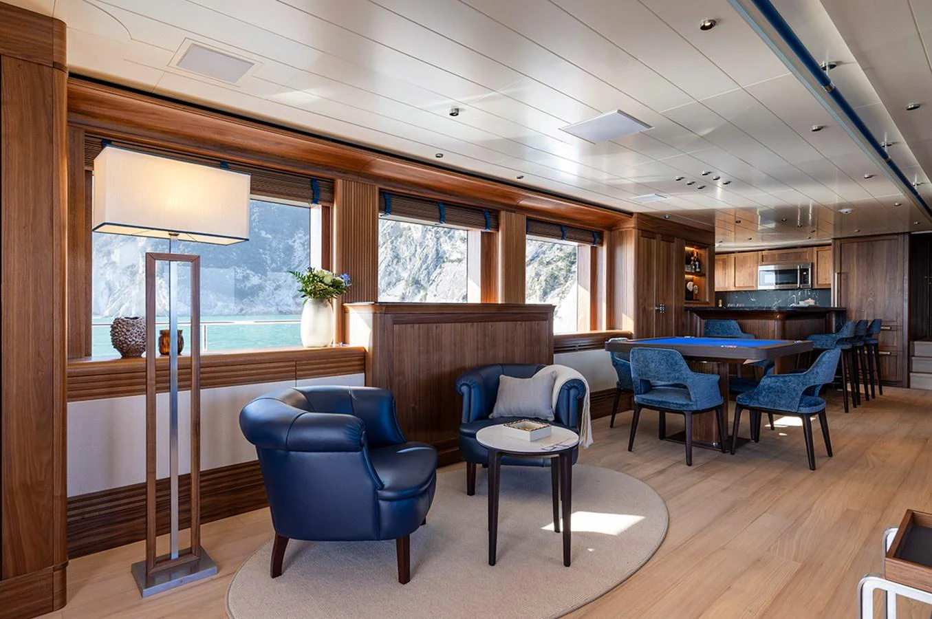 The yacht's salon features elegant furnishings with a mix of wood and blue accents, offering a comfortable and stylish space for relaxation. aboard EMPIRE Yacht for Sale
